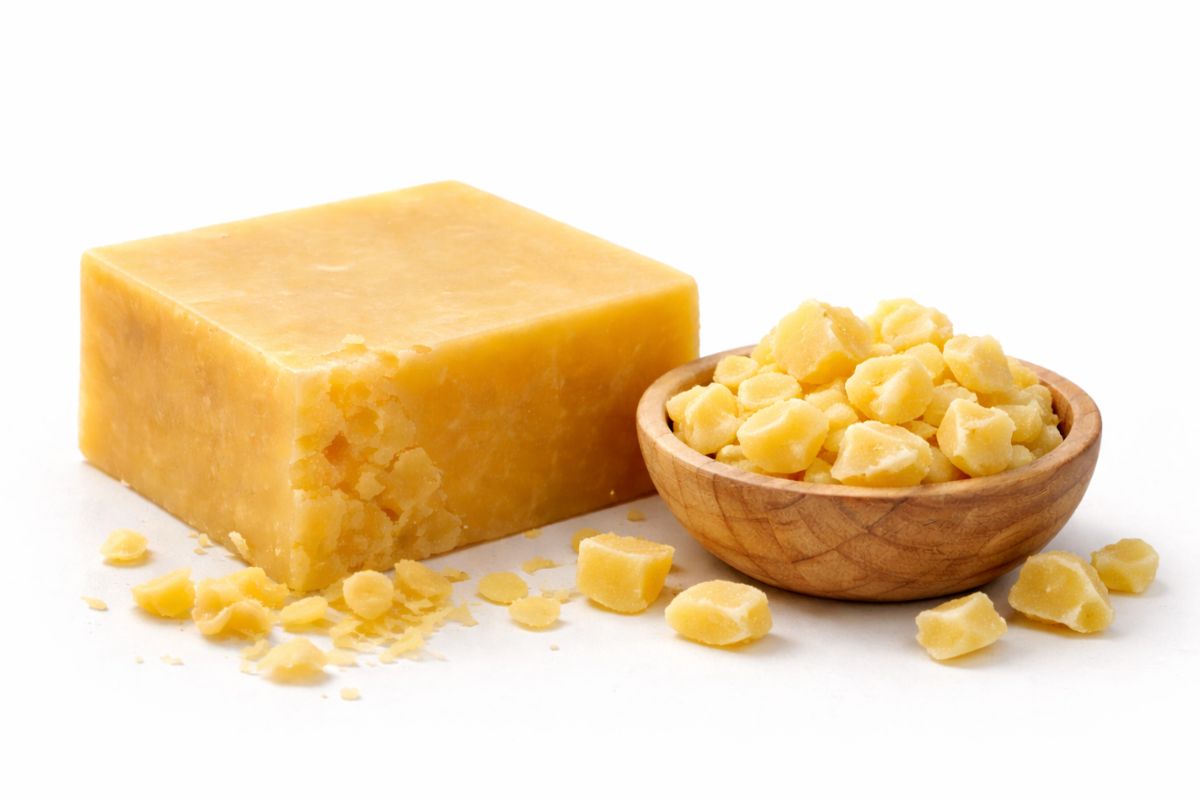 Block of yellow soap and a wooden bowl with soap pieces on a white background
